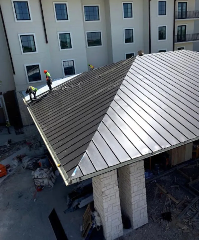 Crew installing standing seam metal roof panels on a commercial project in Baldwinsville